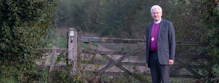 Bishop Colin standing by a gate