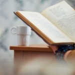 A person reading is slightly obscured by books in the foreground